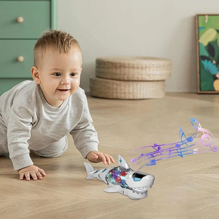 Small child crawling towards the Electric Gear Shark toy on a wooden floor